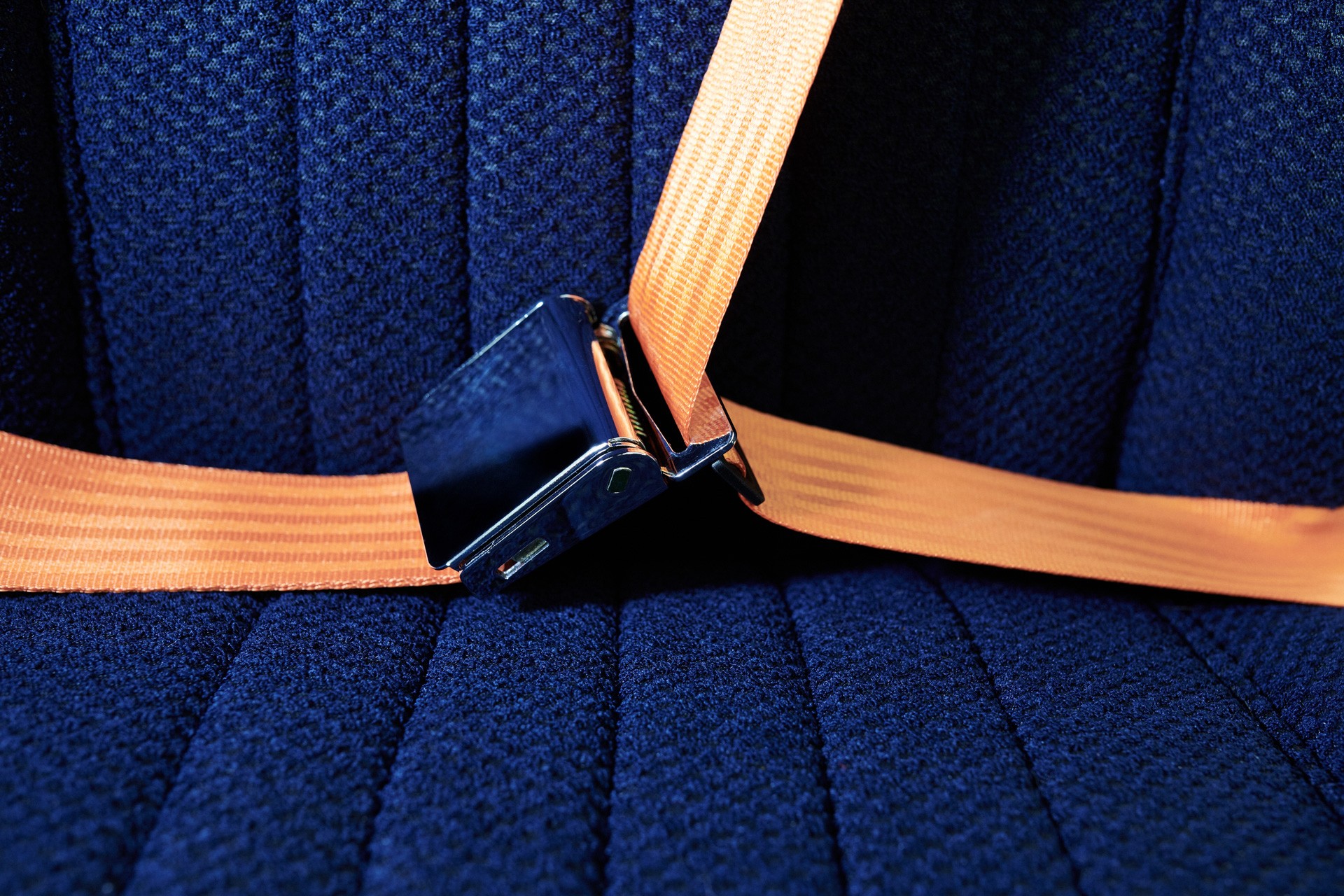 Close-up of the orange seatbelts in contrast to the elegant dark blue seats. 